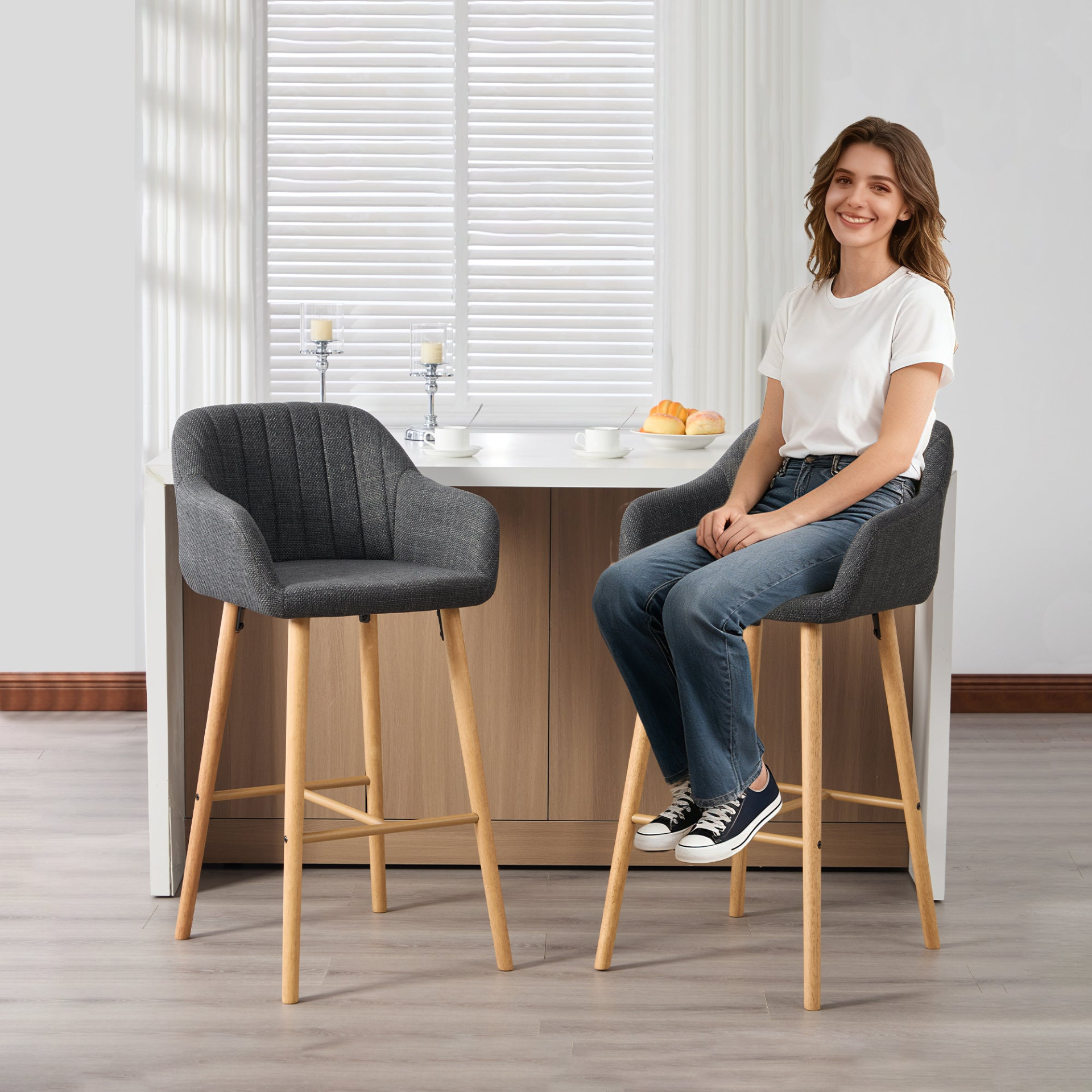 Modern linen upholstered bar stool by Start2Finish with back, armrests, footrest, and solid wood legs shown from a side angle.
