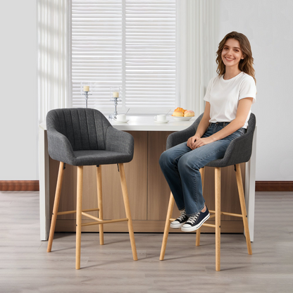 Modern linen upholstered bar stool by Start2Finish with back, armrests, footrest, and solid wood legs shown from a side angle.