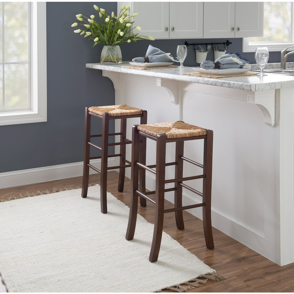Set of two Gianna backless walnut barstools by Start2Finish, featuring sleek wooden seats and sturdy legs, shown from a side angle.