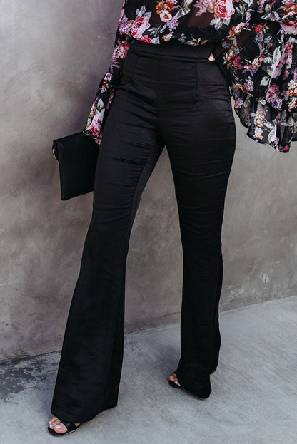 Black satin flare tailored pants from Harlequin Daisy, shown on a model, featuring a sleek fit and elegant design for Bath &amp; Beauty.