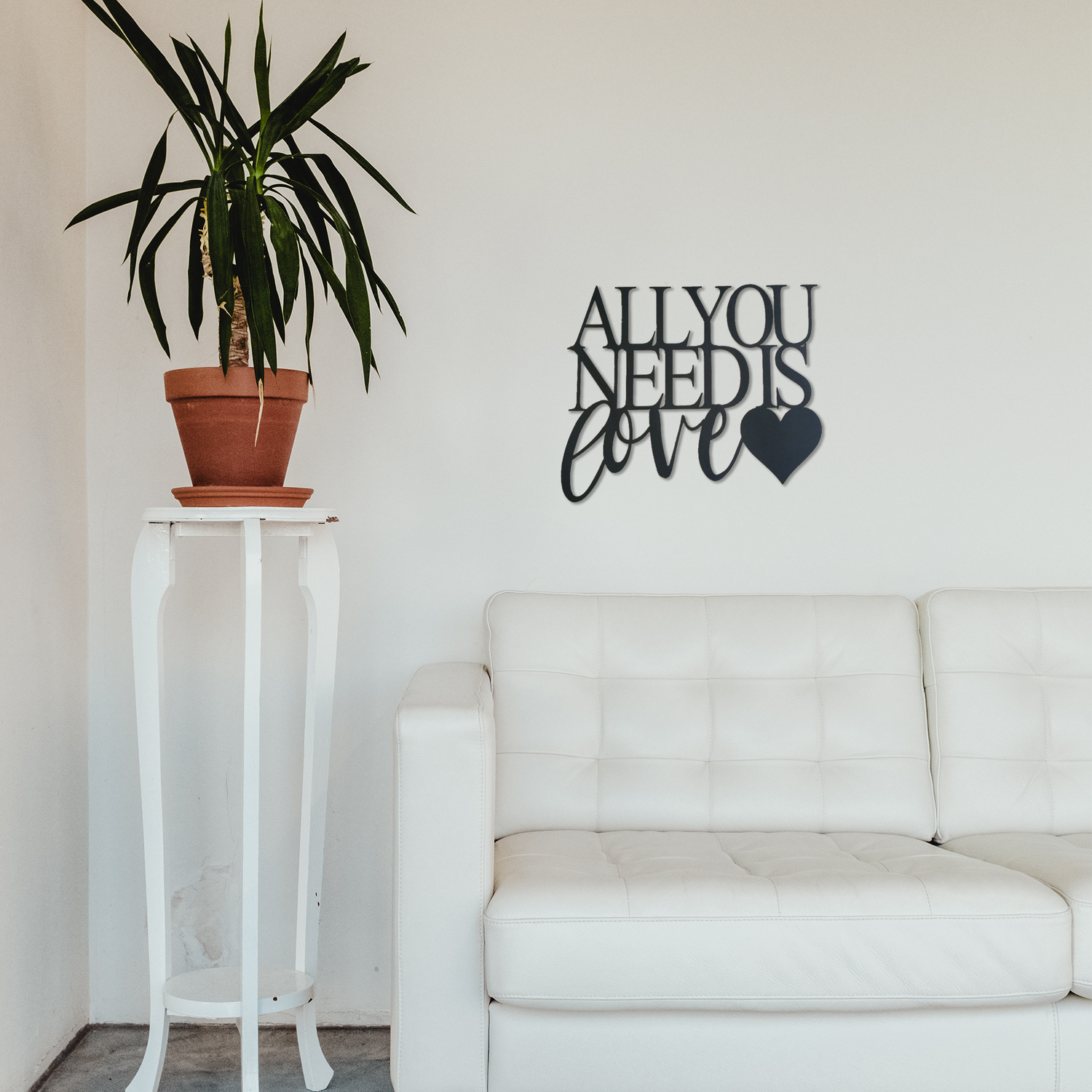 Malachite metal wall art with "All You Need Is Love" lettering hanging above a cozy couch in home decor setting.